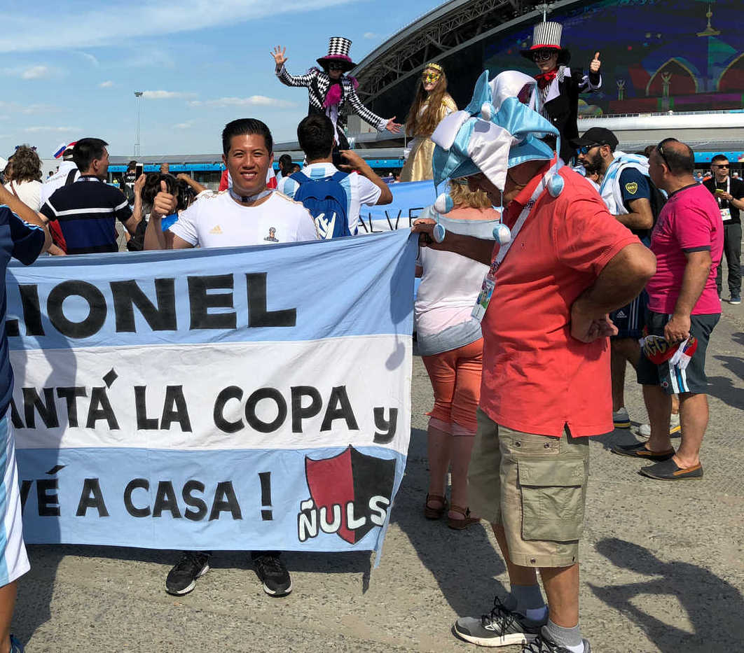 A smiling Argentina soccer fan holds a large banner for Lionel Messi at the 2018 World Cup.