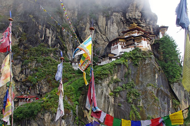 Tiger's Nest Monastery in Bhutan built into a misty cliffside with colorful prayer flags.