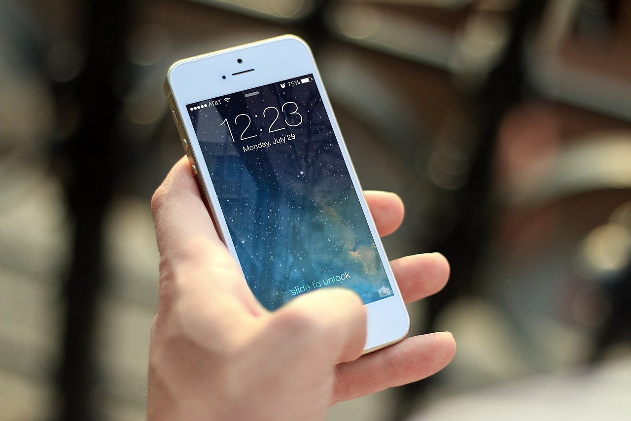 A hand holds a white smartphone displaying its lock screen with the time and a starry background.