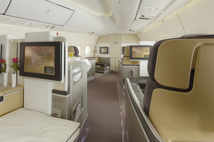 Interior of a luxurious airplane cabin with spacious seats and personal screens.